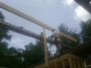 Carpenter setting a ridge beam over a new addition frame — Ice Dam Removal by Roofing Brothers in Lakeshore
