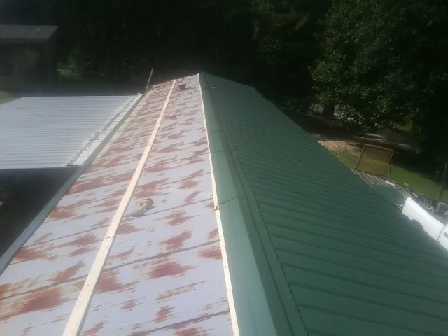 Old rusted panels beside newly installed green metal roofing — Wind Damage Roof Repair by Roofing Brothers in Lakeshore