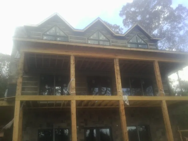 Dormers and porch framing on a large log home under construction — Roof Coating work by our crew in Lakeshore