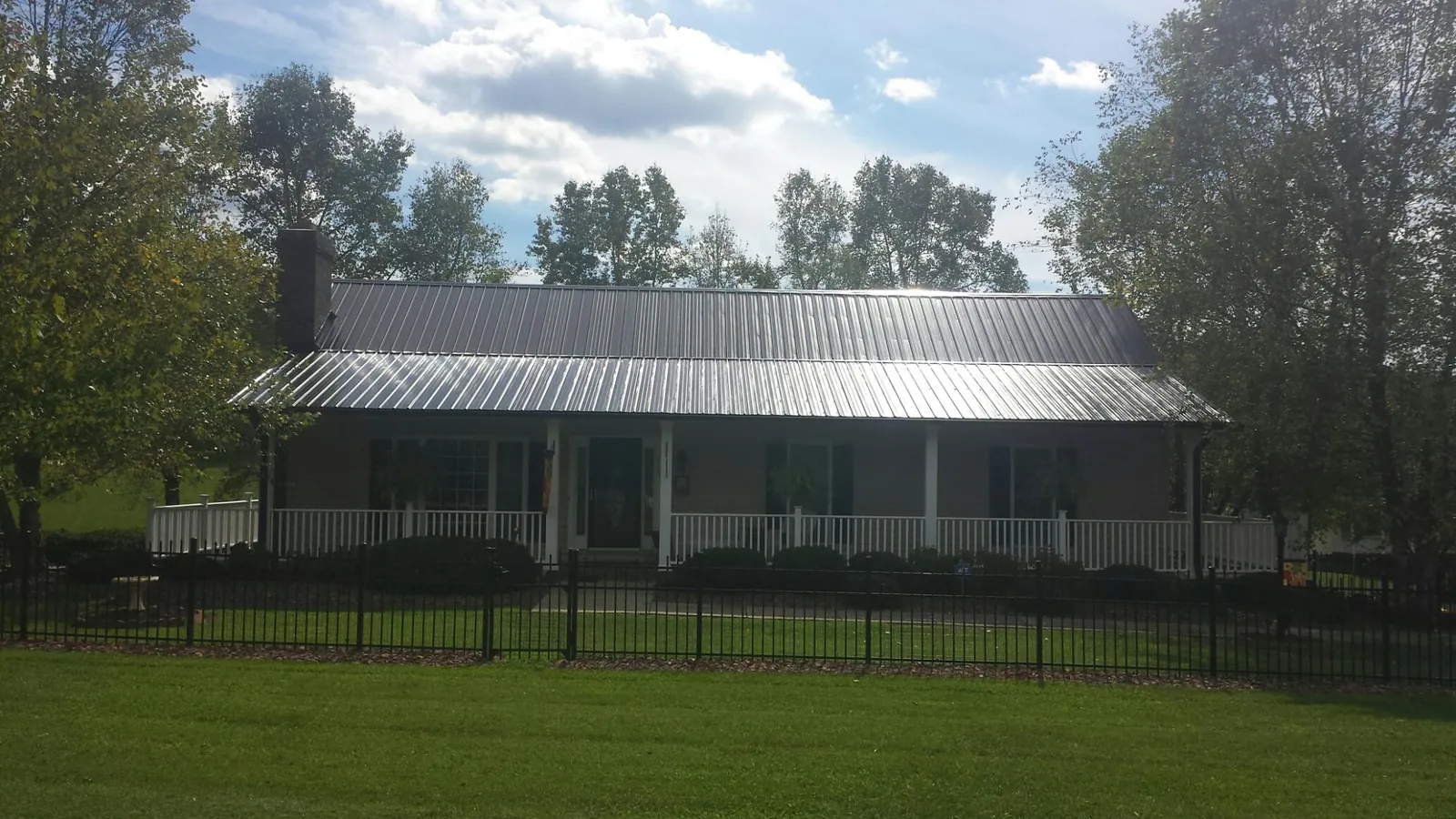 Gray metal roof on a brick ranch with a full width front porch — Gutter Guard Installation work by our crew in Lakeshore
