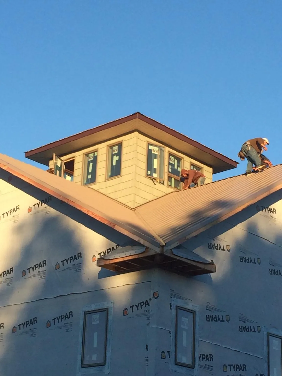 Roofers working around a rooftop cupola on a new metal roof at sunset — Roof Waterproofing in Lakeshore by Roofing Brothers